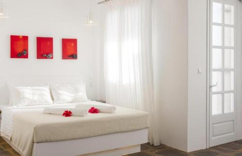 a white bedroom with a bed with red flowers on it at Scorpios Hotel & Suites in Samos