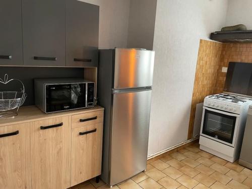 a kitchen with a stainless steel refrigerator and a microwave at Appartement au bord du lac avec terrasse in La Tour-dʼAuvergne