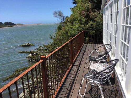 two chairs and tables on a balcony overlooking the water at 'Erinleigh By The Sea' Waterfront in Jenner