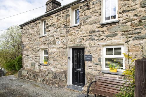 a stone house with a bench in front of it at Pen-Y-Bryn Cottage in Blaenau-Ffestiniog