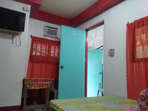 um quarto com uma cama, uma janela e uma televisão em Jammers Pension House em El Nido