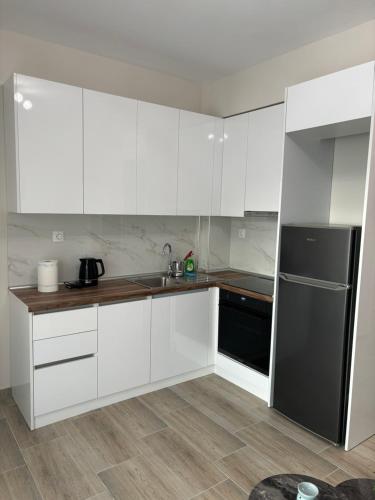 a kitchen with white cabinets and a black refrigerator at Anna-Maria Appartement in Kalives Poligirou