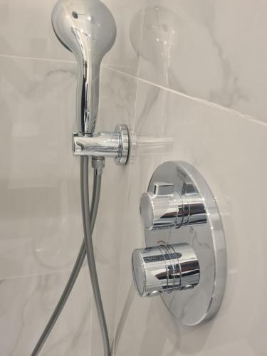 a shower with a chrome shower head on a wall at Luxury studio flat in London