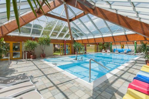 an indoor swimming pool with a glass roof at Residence Samont in Arta Terme