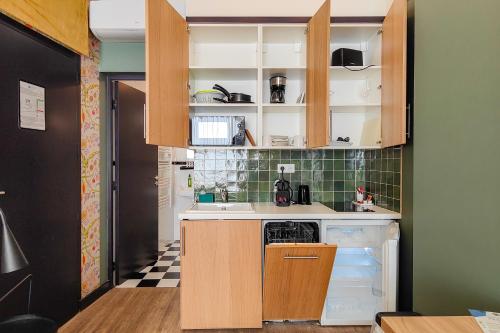 a kitchen with wooden cabinets and an open refrigerator at Hôtel de France, un hôtel AMMI in Nice