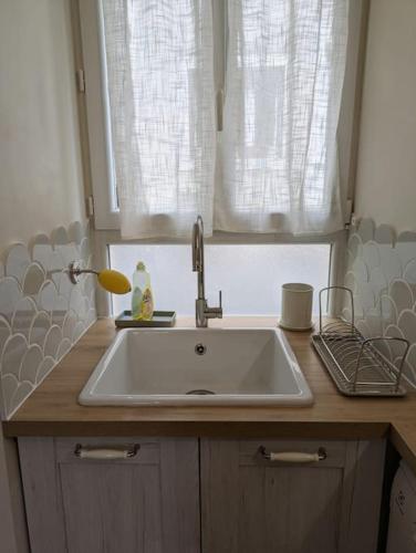 un comptoir de cuisine avec un évier et une fenêtre dans l'établissement Appartement avec jardin et accès mer, à Grandcamp-Maisy