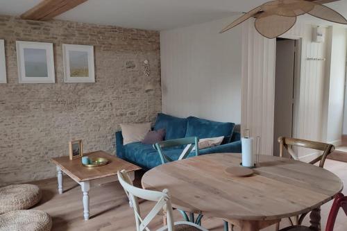 a living room with a table and a blue couch at Appartement avec jardin et accès mer in Grandcamp-Maisy