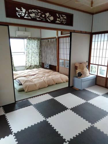 1 dormitorio con 1 cama y suelo a cuadros en ゲストハウスジェイズ en Amagi