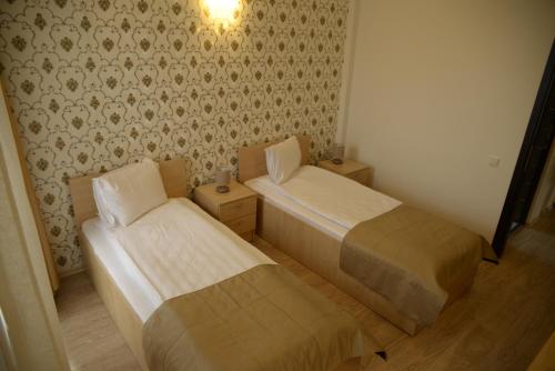 two beds in a small room with wallpaper at Hotel Story in Târgu Jiu