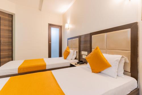 2 łóżka w pokoju hotelowym z żółtymi poduszkami w obiekcie Hotel Prime w mieście Ahmadabad
