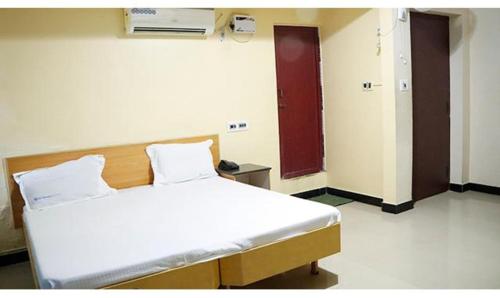 a hospital room with a bed and a red door at FabExpress Sivabhagya Annex in Madurai