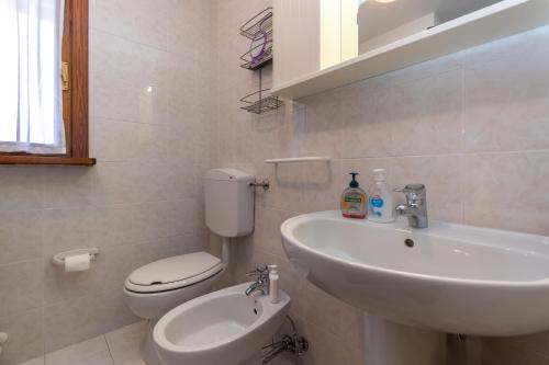 a white bathroom with a toilet and a sink at Maison Miravalle in Colle Santa Lucia