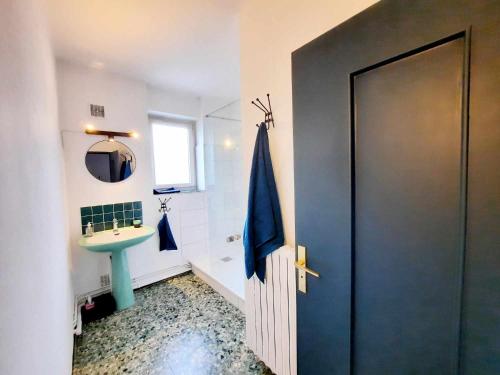 La salle de bains est pourvue d'une porte bleue et d'un lavabo. dans l'établissement La maison du bord, à Bellac