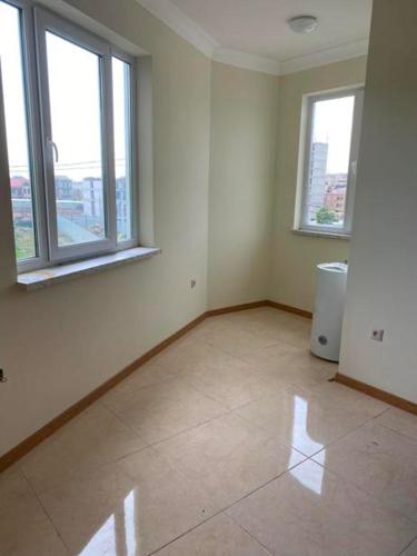 um quarto vazio com duas janelas e piso em azulejo em Cosy and calm em Yerevan
