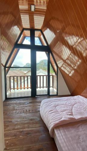 Bett in einem Zimmer mit einem großen Fenster in der Unterkunft AGRIYA LUBIS CABIN in Diyeng