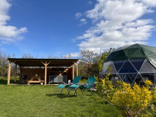 a group of chairs and a tent in a field at Geodesic Dome Glamping in Llanidloes