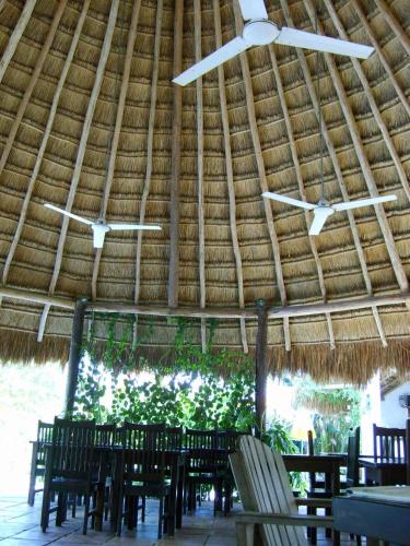 a straw roof with tables and chairs in a restaurant at Casa Don Diego in Tulum