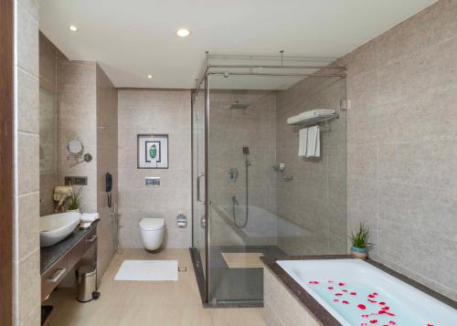 a bathroom with a tub and a shower and a sink at Distrikt 9 in Palakkad