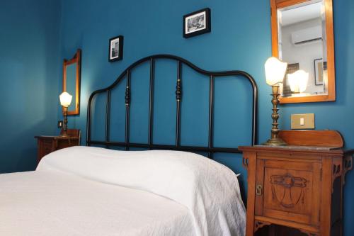Dormitorio azul con cama, tocador y espejo en La Via delle Biciclette, en Palermo