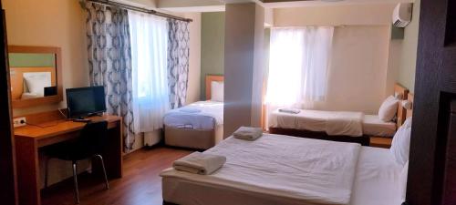 Habitación de hotel con 2 camas y escritorio con ordenador en MD CITY HOTEL, en Canakkale