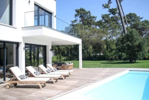 a group of lounge chairs sitting next to a swimming pool at Villa La Foret Du Lac à HOSSEGOR in Soorts-Hossegor