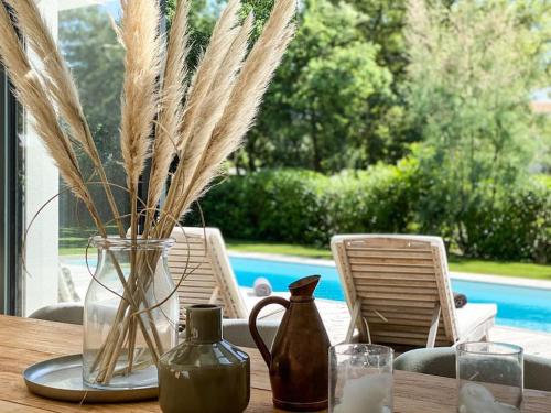 a wooden table with a vase with grass in it at Villa La Foret Du Lac à HOSSEGOR in Soorts-Hossegor
