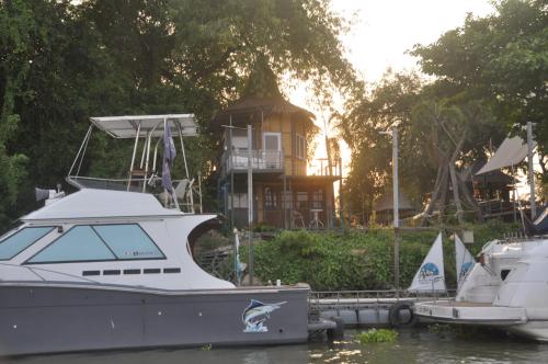 a boat docked at a dock with a house in the background at ayutthaya river camp and yacht charter in Ban Khlong Suan Phlu