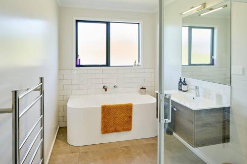 a white bathroom with a tub and a sink at Tranquility on the Hill Outdoor Bath 30 mins to city by train or car in Wellington