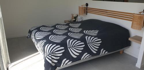 a bed with a black and white blanket on it at Les Suites du XV in Cap d'Agde