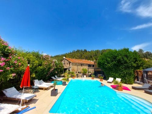 une piscine avec des chaises et des parasols ainsi qu'une maison dans l'établissement La Bergerie Du Moulin, à Taradeau