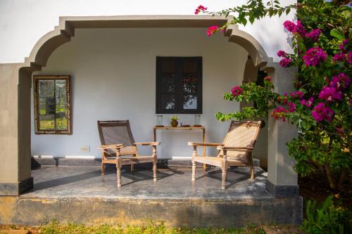 a patio with two chairs and a table and flowers at Isla's Ridge - A CGH Earth SAHA Experience in Kodaikānāl