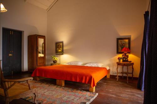 a bedroom with a bed with a red blanket at Isla's Ridge - A CGH Earth SAHA Experience in Kodaikānāl