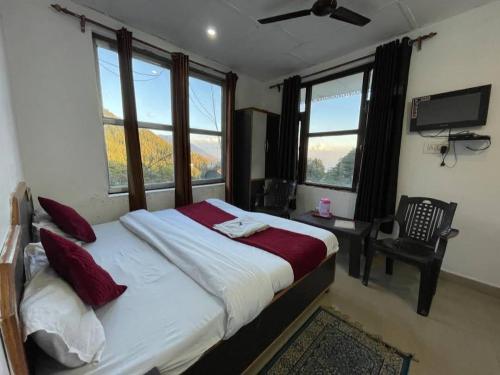 una camera con un grande letto con finestre e una TV di The Lake Cottage by VRB Hotels a Dharamshala
