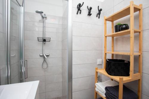 a bathroom with a shower and a wooden shelf at Studio Apartment Mia in Rabac