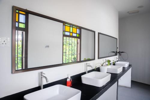 a bathroom with two sinks and two mirrors at Sleep Here Hostel, Melaka in Malacca