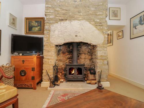 a stone fireplace in a living room with a tv at Market Place Cottage, Tetbury, Cotswolds Grade II Central location in Tetbury