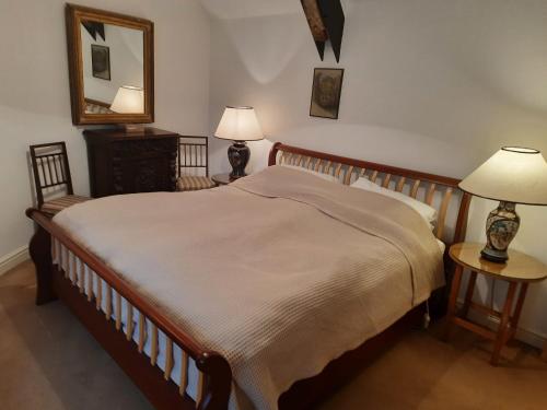 a bedroom with a large bed and two lamps and a mirror at Market Place Cottage, Tetbury, Cotswolds Grade II Central location in Tetbury
