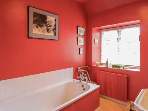 Market Place Cottage, Tetbury, Cotswolds Grade II Central location في تيتبري: حمام احمر مع حوض استحمام ونافذة