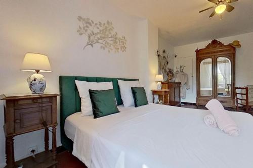 a bedroom with a large bed with green and white pillows at Les 2 Drôles d'Oiseaux in Luc-sur-Orbieu