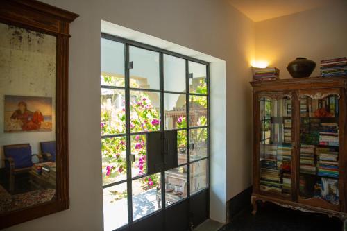 a room with a window with flowers and a book shelf at Isla's Ridge - A CGH Earth SAHA Experience in Kodaikānāl