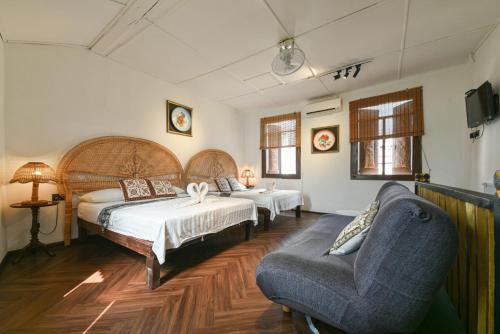 a bedroom with two beds and a couch and a chair at Ohana House @ 31 Jawa in Melaka