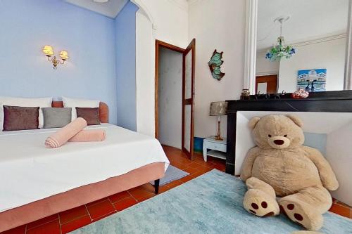 a teddy bear sitting on the floor of a bedroom at Les 2 Drôles d'Oiseaux in Luc-sur-Orbieu