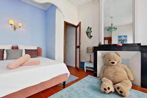 a teddy bear sitting on the floor in a bedroom at Les 2 Drôles d'Oiseaux in Luc-sur-Orbieu