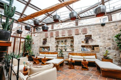 a conservatory with couches and tables and a brick wall at Millstone Cave Suites Hotel in Uchisar
