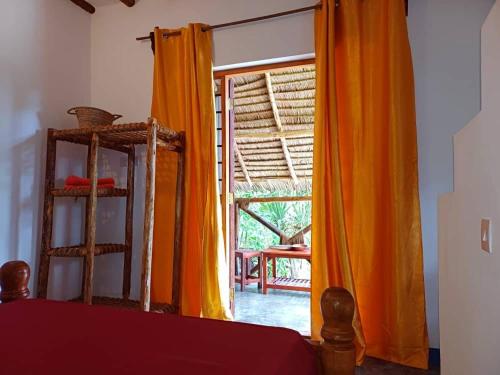 a bedroom with an open door with an orange curtain at Karibu Paradaizi in Michamvi