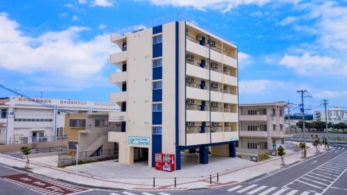 a tall white building on a city street at Luana Uakoko Resort 旧 EmiFull Resort in Chatan