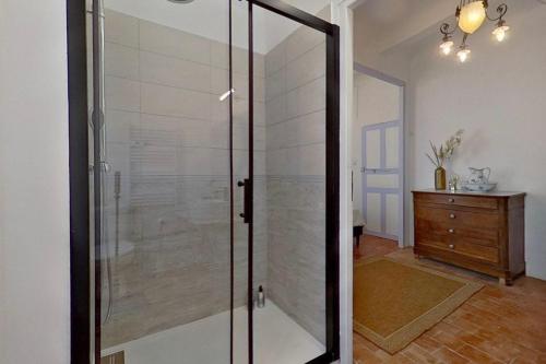 a glass shower stall in a room with a dresser at Les 2 Drôles d'Oiseaux in Luc-sur-Orbieu