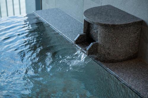 a pool of water with a stone fountain at La Vista Tokyo Bay in Tokyo