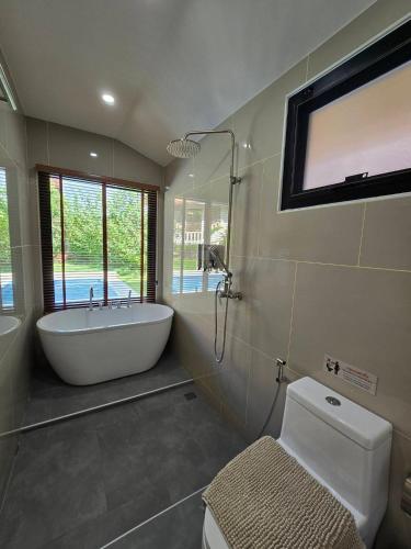 a bathroom with a tub and a toilet and a window at PoolVilla 234 Patong in Patong Beach