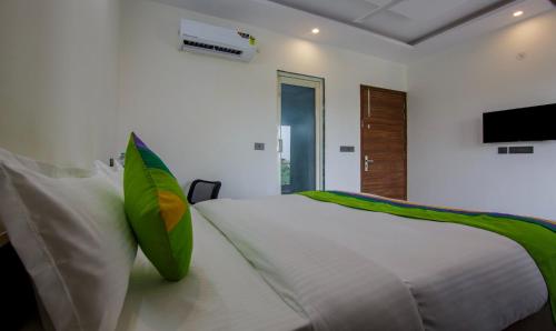 Dormitorio blanco con cama con almohadas verdes y blancas en Hotel Grand Vista en Noida